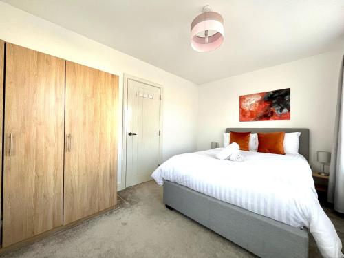 a bedroom with a large bed and a wooden cabinet at Lovely 4 doubled bedroomed townhouse in Bicester near to Bicester Village in Bicester