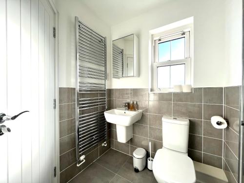 y baño con aseo, lavabo y espejo. en Lovely 4 doubled bedroomed townhouse in Bicester near to Bicester Village en Bicester