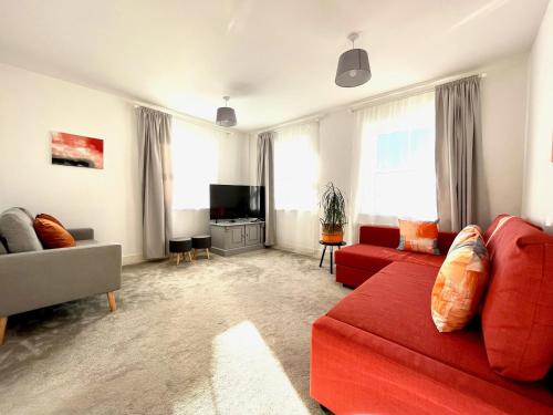 a living room with a red couch and a tv at Lovely 4 doubled bedroomed townhouse in Bicester near to Bicester Village in Bicester