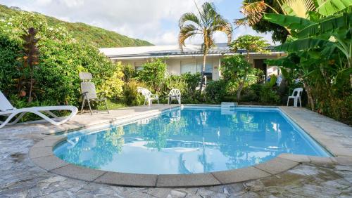 a swimming pool with chairs and a house at Pension De La Plage in Punaauia