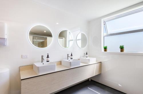 a bathroom with two sinks and two mirrors at Lake Maraetai Lodge in Mangakino