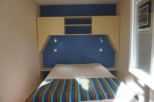 Cette petite chambre comprend un lit avec un mur bleu. dans l'établissement La Pinède Golf, Surf, Vélo, Piscine, à Lacanau