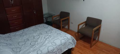 1 dormitorio con cama, silla y vestidor en Capistrano Suites, en Hermosillo
