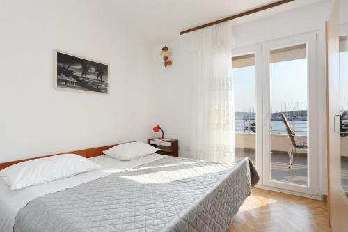 ein weißes Schlafzimmer mit einem Bett und einem Balkon in der Unterkunft Apartment Rogoznica 7558a in Rogoznica