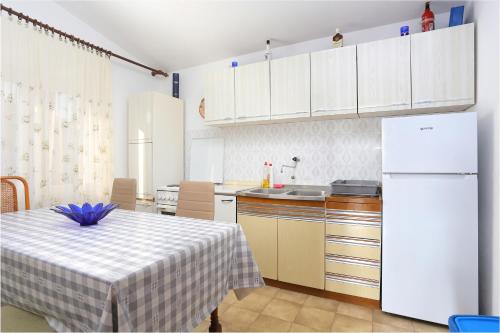eine Küche mit einem Tisch und einem weißen Kühlschrank in der Unterkunft Apartment Rogoznica 7558a in Rogoznica