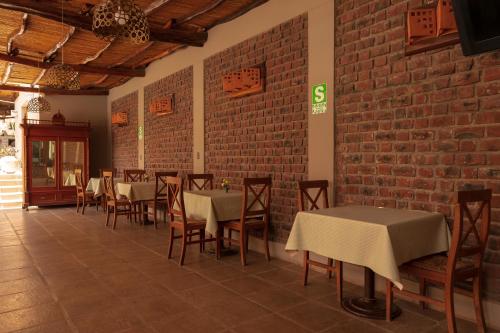 a restaurant with tables and chairs and a brick wall at Hotel El Huacachinero in Ica