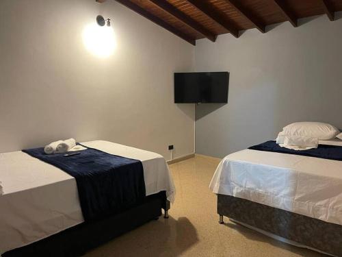 a bedroom with two beds and a flat screen tv at Cozy house en envigado con Jacuzzi in Envigado