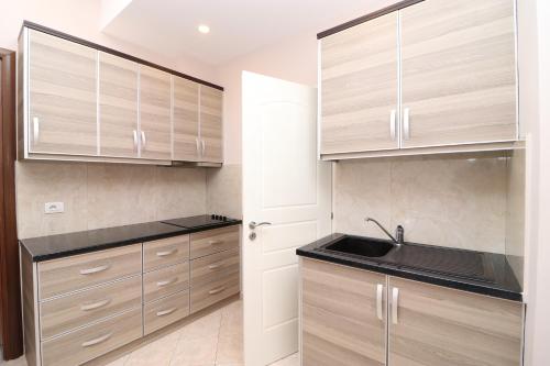 Una cocina con gabinetes de madera y un fregadero. en Vila Bendo, en Divjakë