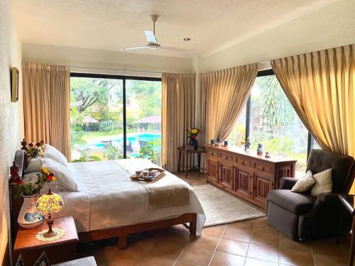 um quarto com uma cama e uma cadeira e uma grande janela em Casa Bienteveo 15 min de Cuernavaca, 23 personas em Tezoyuca