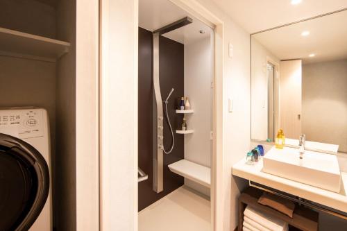 東京的住宿－karaksa hotel colors Tokyo Yaesu，带淋浴、盥洗盆和镜子的浴室