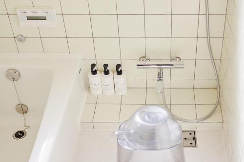 a bathroom with a shower with two bottles on the wall at ritomaru house iki ashibe in Iki
