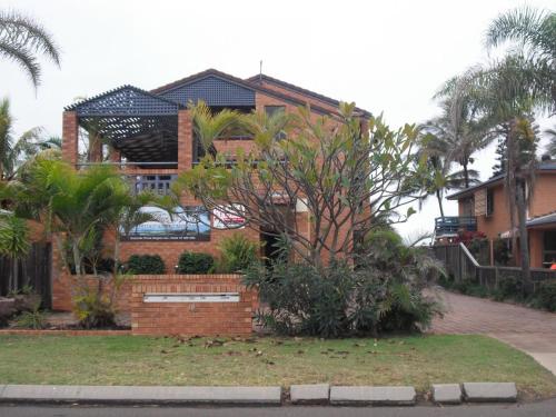 a large brick house with palm trees in front of it at Horizons Unit 2 Beachfront Unit in Bargara