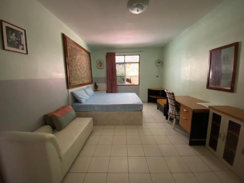 a bedroom with a bed and a couch and a desk at Nan Inn Bungalow in Karon Beach