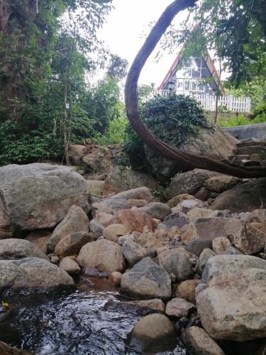 a stream of rocks with a house in the background at Riverston Nature Villa in Rattota