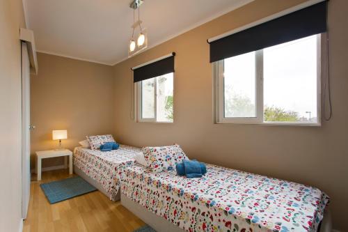 two beds in a bedroom with two windows at Oporto Blue Lapa - Spacious Family Apartment With Winter Garden in Porto