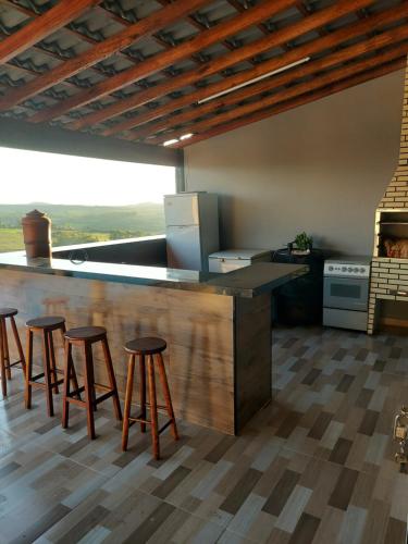 a kitchen with four bar stools and a counter at Chácara do Mirante in São Sebastião do Paraíso