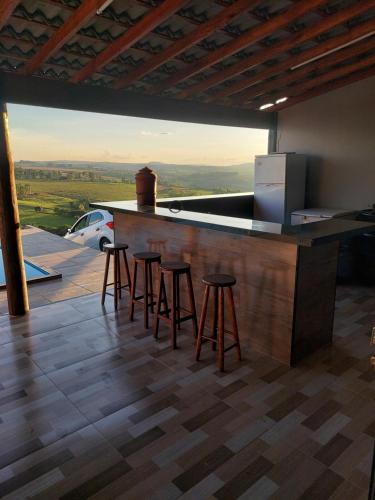 a kitchen with stools at a bar with a view at Chácara do Mirante in São Sebastião do Paraíso