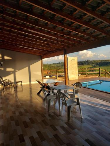 a dining room with a table and chairs and a pool at Chácara do Mirante in São Sebastião do Paraíso