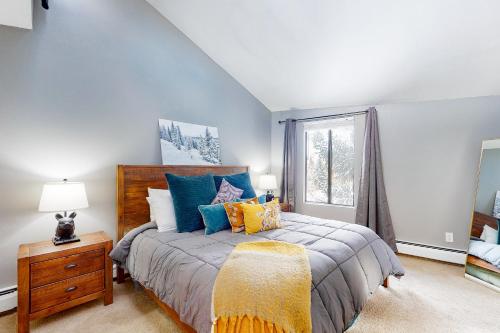 a bedroom with a bed with colorful pillows and a window at Mountainside Oasis in Avon