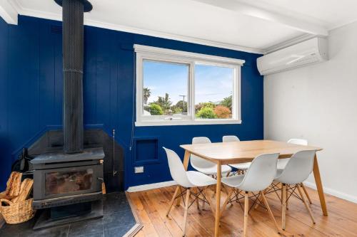 a dining room with a table and a wood stove at Cape Surf House in Cape Woolamai