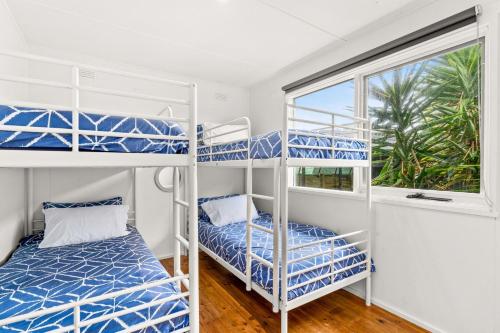 two bunk beds in a room with a window at Cape Surf House in Cape Woolamai