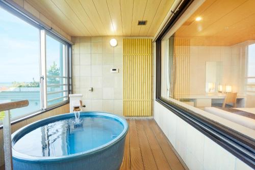 eine große blaue Badewanne in einem Zimmer mit einem Bett in der Unterkunft KAMENOI HOTEL Oarai in Oarai