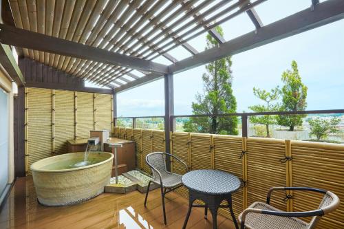 a bathroom with a tub and a table and chairs at KAMENOI HOTEL Oarai in Oarai