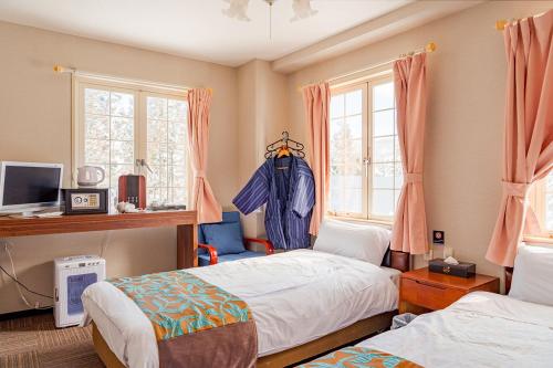 a bedroom with two beds and two windows at Hakuba Sun Valley Hotel Annex in Hakuba