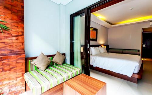 a bedroom with a bed and a couch in a room at Grand Mirah Boutique Hotel in Denpasar