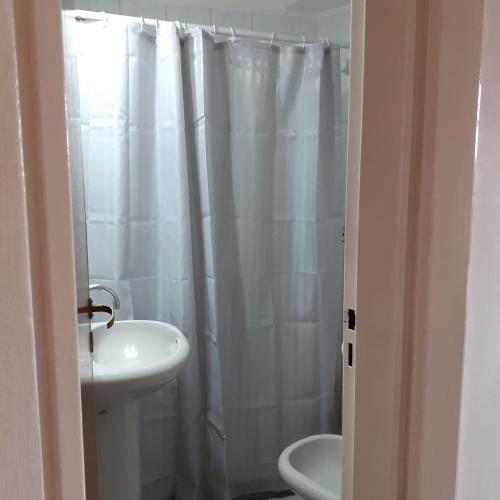 baño con cortina de ducha blanca y lavamanos en Departamento Villanueva en Godoy Cruz