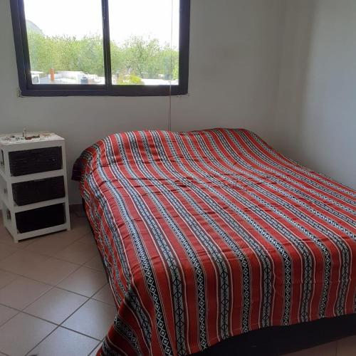 1 cama con manta a rayas en una habitación con ventana en Departamento Villanueva en Godoy Cruz