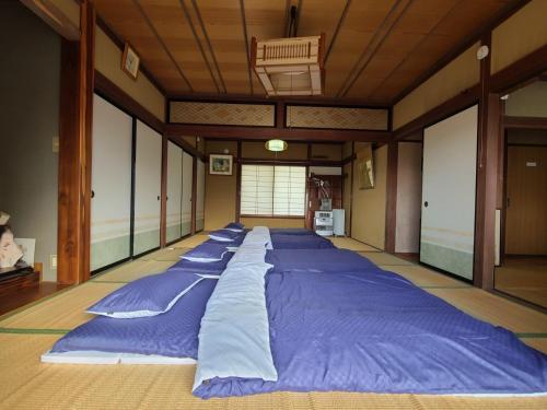 ゲストハウス陽だまりの宿 في Tomi: سرير كبير في غرفة مع وسائد زرقاء