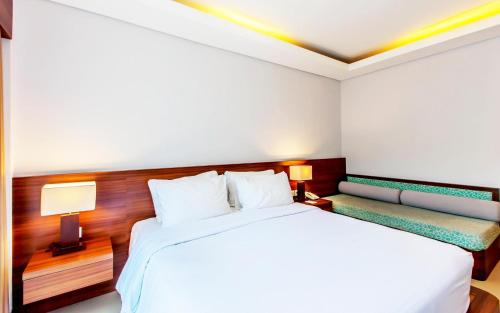 a hotel room with a bed and a bench at Grand Mirah Boutique Hotel in Denpasar