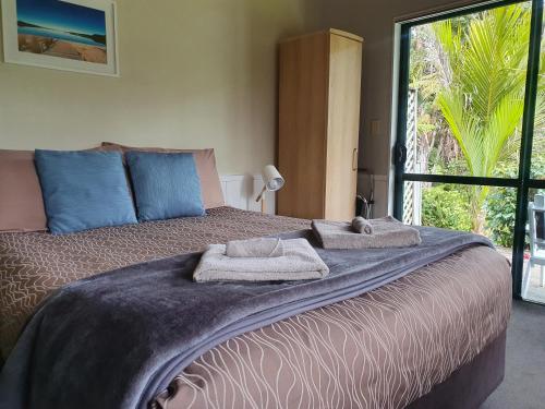 Kauri Coast TOP 10 Holiday Park في Kaihu: غرفة نوم بسرير كبير عليها مناشف