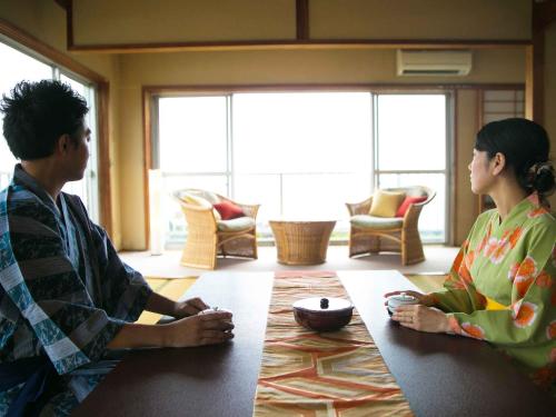 a man and woman sitting at a table in a room at Iseebisou in Ibusuki
