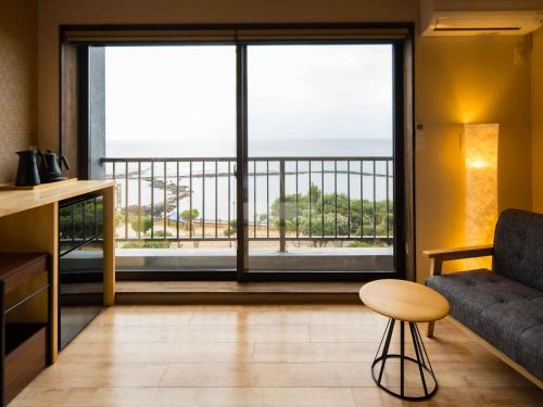 a living room with a couch and a large window at Iseebisou in Ibusuki