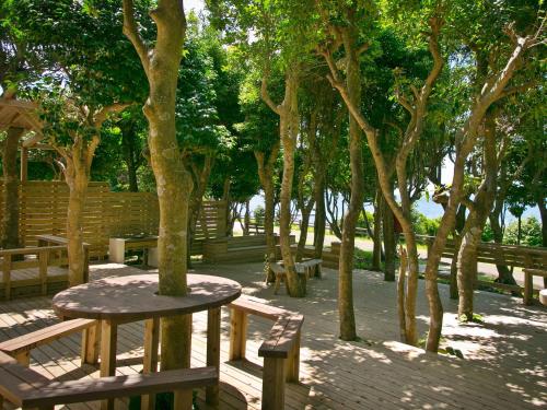 a picnic table and benches in a park with trees at Iseebisou in Ibusuki