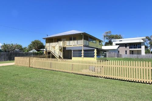 a house with a wooden fence in front of a yard at Billys Beach House Elliott Heads in Elliott Heads