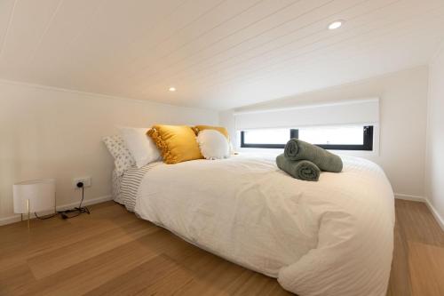 um quarto com uma grande cama branca com almofadas amarelas em Husky Tiny Home by Experience Jervis Bay em Huskisson