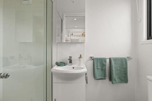 a white bathroom with a sink and a shower at Husky Tiny Home by Experience Jervis Bay in Huskisson