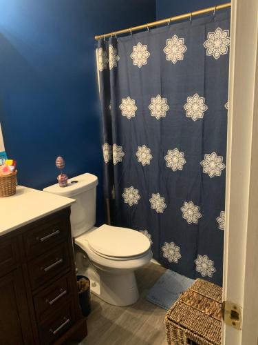 a bathroom with a toilet and a blue shower curtain at Captivating Home near Downtown ATL in Conley
