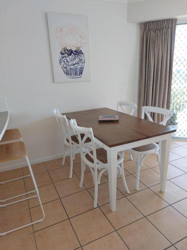 a dining room table with white chairs and a table at Sandy Shores Holiday Units in Caloundra