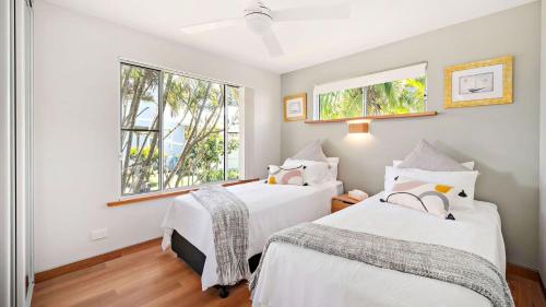 two beds in a room with two windows at Sunset Sails Taylors Beach NSW in Taylors Beach
