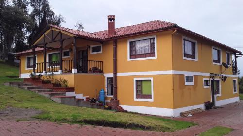 a yellow house with a red roof at Quinta Los Llanitos Hospedaje Campestre in Guatavita