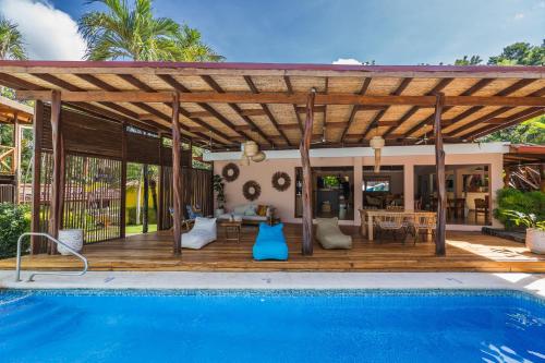 eine Holzterrasse mit einem Pool neben einem Haus in der Unterkunft Hotel Arco Iris in Tamarindo