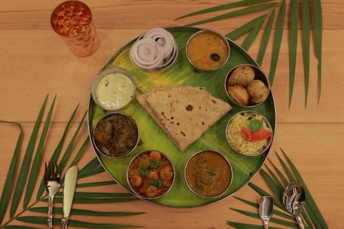 a green plate with different types of food on a table at Wooden ECR Sea Resort in Puducherry