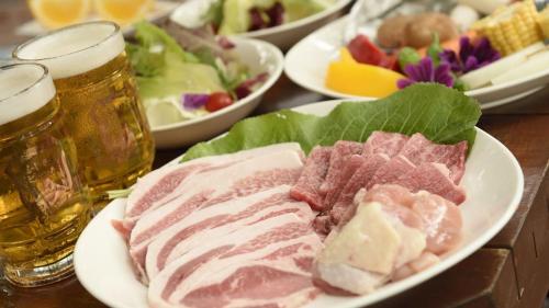a table topped with plates of meat and glasses of beer at PICA Yamanakako Village in Yamanakako