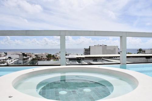 a bath tub on a balcony with a view of the ocean at Ceren Luxury Apartments at Fifth Avenue by Spot Rentals in Playa del Carmen