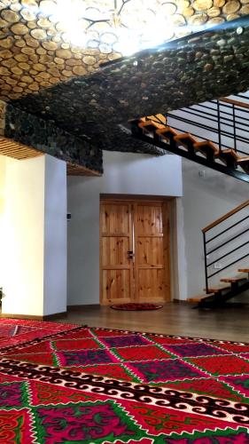 a large room with a rug in front of a door at Kezgin Guest House in Naryn