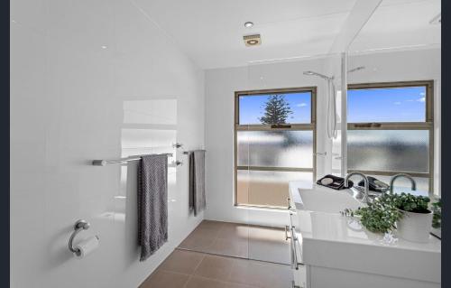 a white bathroom with a sink and a window at Sea View - Absolute Beachfront Shellharbour in Shellharbour